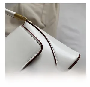 Detailed macro view of white leather underarm bag with brown oil edges and golden hardware
