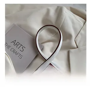 Detail of white leather strap with dark brown edges and golden metal hardware