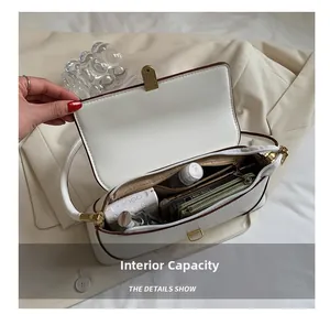 Detail showing internal capacity of the white baguette bag with various daily essentials