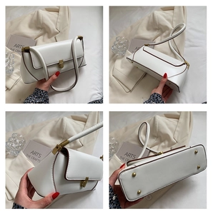 Detail view of white PU leather bag with gold buckle, brown edges and metal feet studs