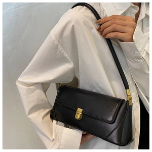 Detail of a vintage black matte leather underarm bag with a gold metal twist lock
