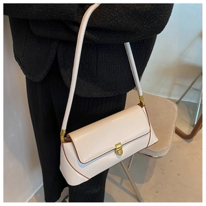 Detail of minimalist beige baguette bag with gold metal buckle and contrast stitching