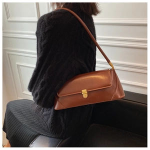 Detail of a vintage reddish-brown leather baguette bag with a golden metal buckle