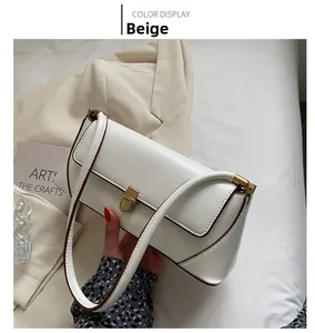 Detail of beige faux leather baguette bag featuring a gold metal clasp and fine stitching