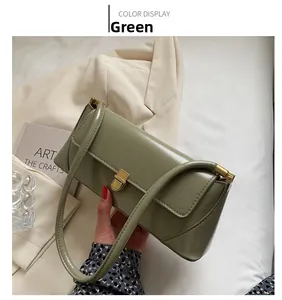 Detail of green leather baguette bag featuring a gold metal buckle and shoulder strap