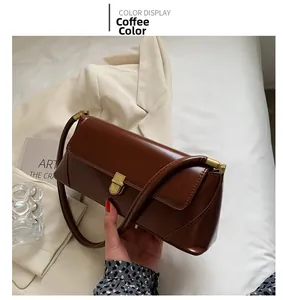 Detail of vintage brown baguette shoulder bag with gold metal buckle and leather texture
