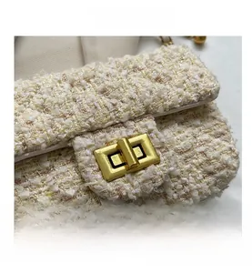 Detail of the golden metal twist lock and textured tweed fabric on women's shoulder bag
