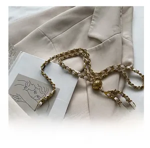 Detail of adjustable gold metal ball buckle and tweed chain strap on a stylish crossbody bag