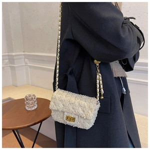 Detail of tweed chain bag with gold hardware clasp and quilted pattern texture