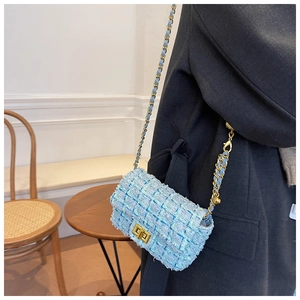 Detail of light blue tweed crossbody bag with golden chain strap and metallic swivel lock