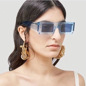 Detail shot of blue square sunglasses with metallic rivets and layered gold hoop earrings