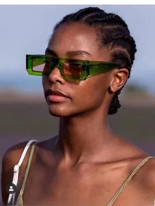 Close-up of green resin square sunglasses with orange lenses on model outdoors