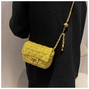 Detail of yellow tweed mini bag featuring gold-tone hardware and adjustable ball chain
