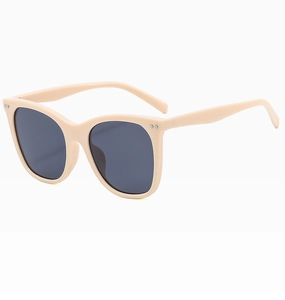Detail view of beige cat-eye sunglasses with dark UV lenses and silver dot accents