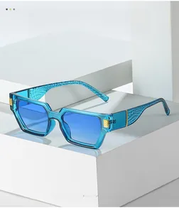 Detail of blue square sunglasses showing crocodile texture and gold metal temple accents