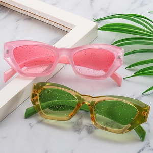 Detail of pink and green cat eye sunglasses with glitter lenses on marble