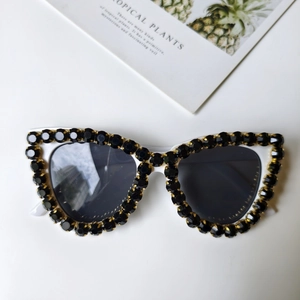 Makro-Detail einer weißen Cat-Eye-Sonnenbrille mit schwarzen Strasssteinen und Gläsern