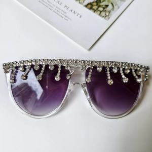 Detailaufnahme der Oversized-Sonnenbrille mit lila Verlaufsgläsern und silbernen Strass-Quasten