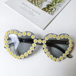 Detailansicht der herzförmigen Sonnenbrille mit 3D-Gänseblümchen-Rahmen auf weißem Hintergrund