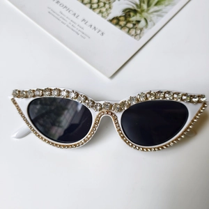 Detail der weißen Cat-Eye-Sonnenbrille mit luxuriösen Strasssteinen und dunklen Gläsern