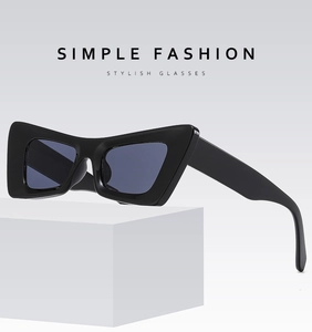 Lunettes de soleil cat-eye noires surdimensionnées avec verres UV sur bloc blanc