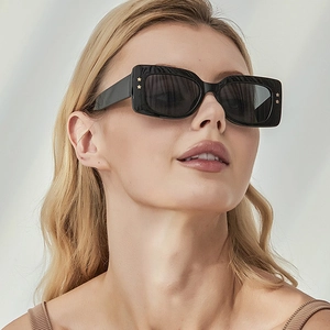 Close-up of black square sunglasses with gold star rivets on trendy thick frame