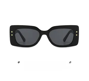 Detail of black rectangular sunglasses featuring gold star metal rivets on frame
