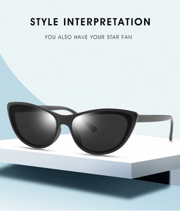 Detail of sleek black cat-eye sunglasses on a white display stand with light blue backdrop