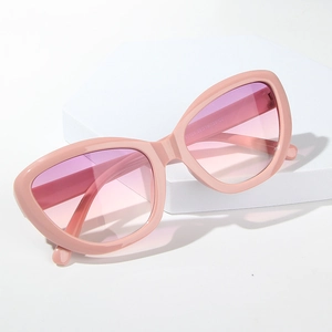 Pink cat eye sunglasses with gradient lenses displayed on a white geometric platform