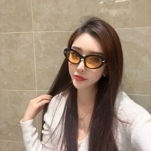 Lunettes de soleil œil de chat rétro à monture noire et verres orange portées par un modèle