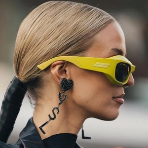 Futuristic Y2K wrap sunglasses in bright yellow with chic YSL logo tassel earrings