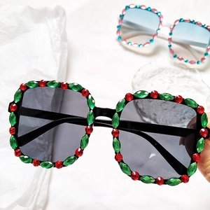 Close-up of square kids sunglasses with sparkling red and green rhinestone decorations