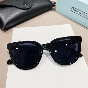 Retro black oversized sunglasses with dark lenses and leather case on beige background
