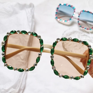 Detail of cream square sunglasses frame featuring green marquise rhinestones and crystals