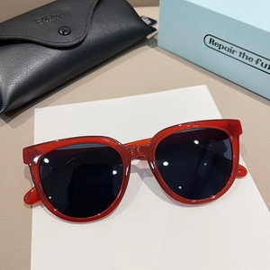 Close-up of retro cat-eye sunglasses with red translucent frame and premium leather case