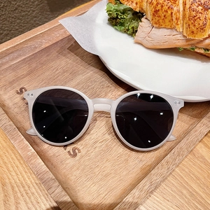 Lunettes de soleil rétro à monture grise mate posées sur un plateau en bois pour le style