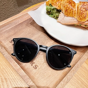 Gros plan de lunettes de soleil rondes rétro noires avec rivets sur un plateau en bois