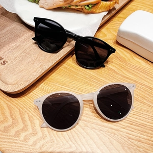 Lunettes de soleil rondes rétro avec rivets en noir et beige sur table bois