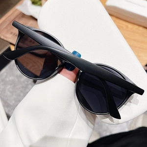 Gros plan de lunettes de soleil rondes noir mat avec protection UV sur support blanc