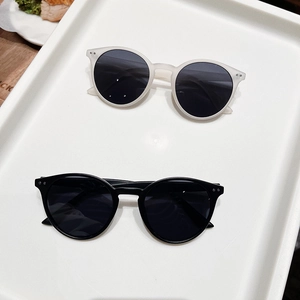 Détail de lunettes de soleil rondes en blanc mat et noir avec rivets métalliques fins