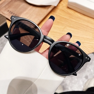Détail de lunettes de soleil rondes vintage noires mates avec rivets en métal argenté