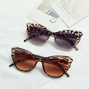 Cat-Eye-Sonnenbrille mit gewellten Rahmen und Leopardenmuster auf weißem Stoff