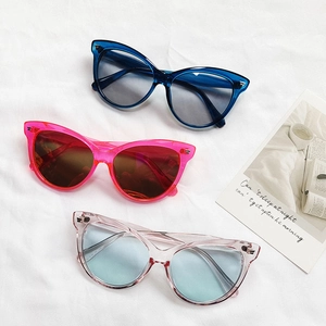 Trois paires de lunettes de soleil œil de chat élégantes en couleurs acidulées sur tissu blanc