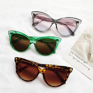 Trois lunettes de soleil œil-de-chat tendance en couleurs acidulées sur tissu blanc