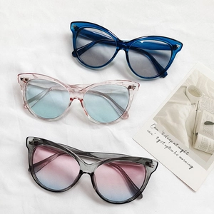Trois lunettes de soleil œil de chat vintage aux couleurs acidulées sur tissu blanc