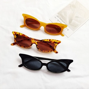 Three pairs of vintage cat-eye sunglasses in yellow, tortoise, and black on a white fabric