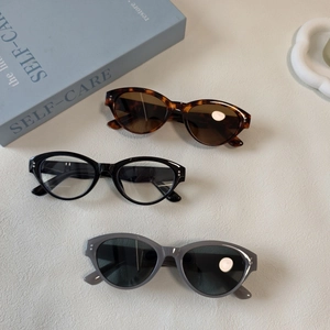 Detailed view of cat eye sunglasses in tortoiseshell and black with metal dot accents