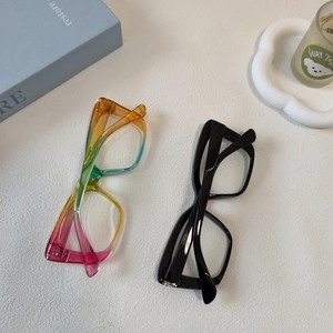 Flat lay of oversized blue light blocking glasses in black and rainbow gradient colors