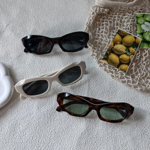 Lunettes de soleil rétro style œil de chat en noir, crème et écaille sur tissu d'été
