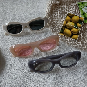 Détail de lunettes de soleil œil-de-chat en crème, rose et gris avec montures géométriques